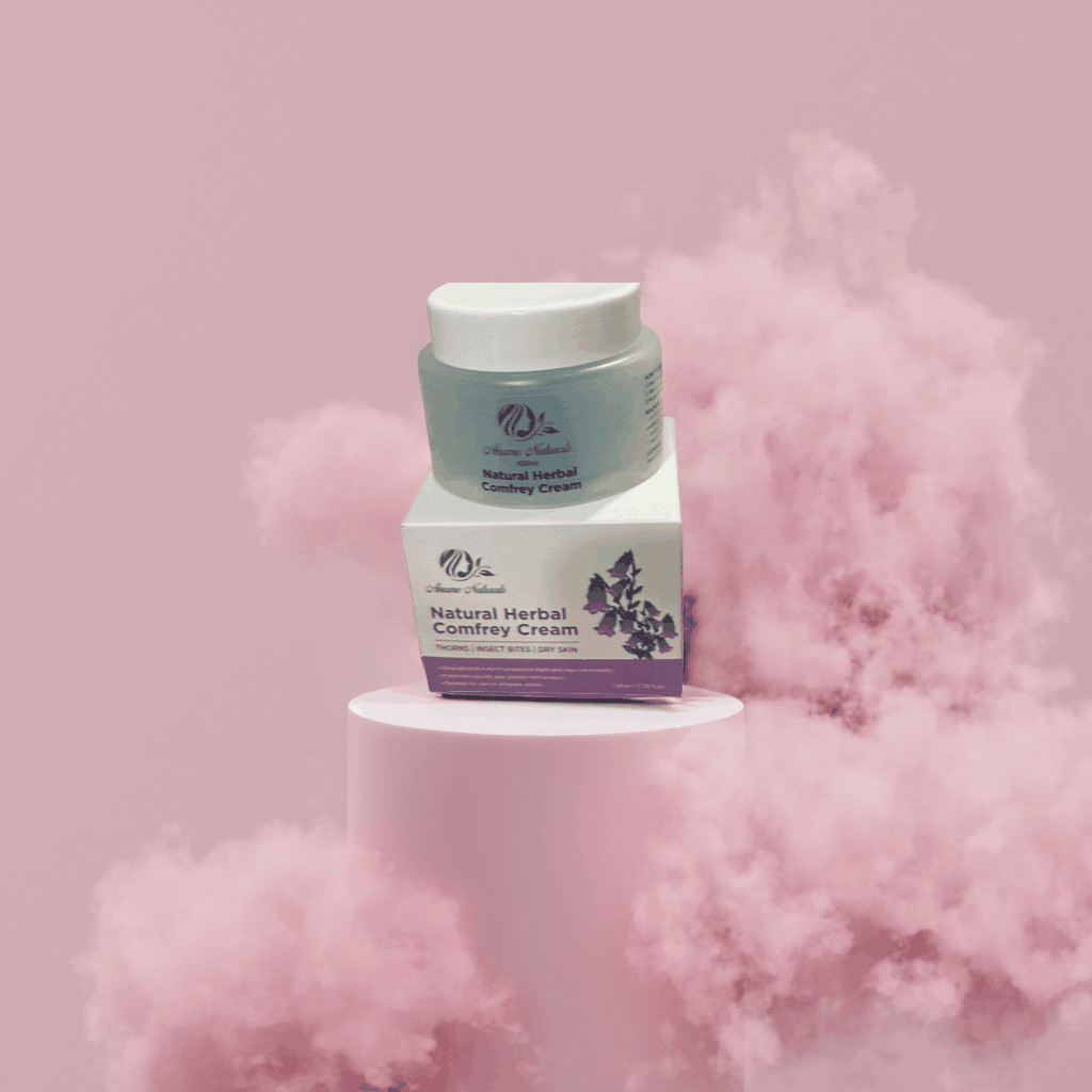 Minty Comfrey Healing Ointment in jar with box on pink smoky background, natural herbal comfrey cream for soothing and healing skin.